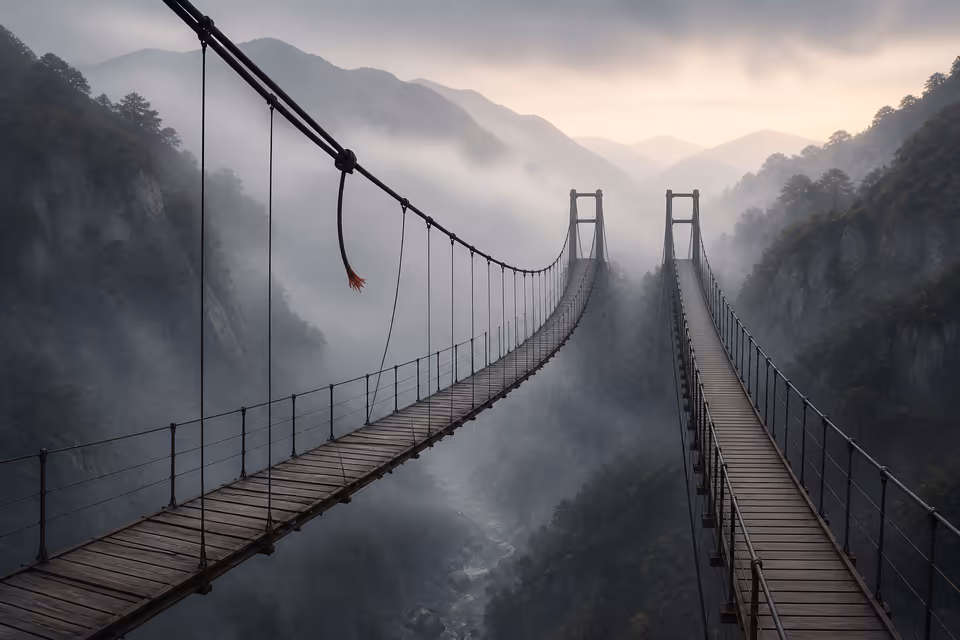Two suspension bridges side by side, the more refined one with a snapped main cable